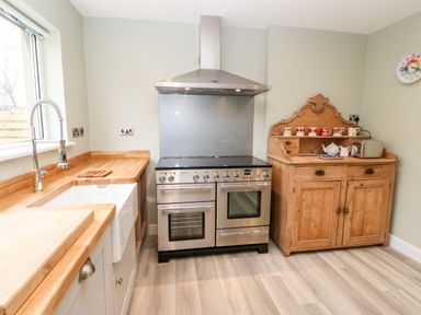 A kitchen with a sink a stove and a wooden cabinet at Willows in Corbridge