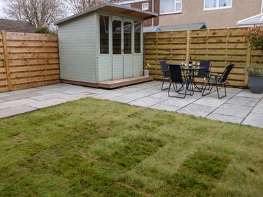 A backyard with a wooden shed a patio with a table and four chairs and a grassy area at Willows in Corbridge