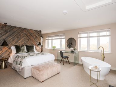 A bedroom with a bed and a glass desk next to a bathtub at The Hayloft in Llanfechell