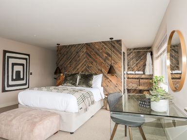 A bedroom with a bed and pillows a glass desk with a chair and a round mirror on the wall at The Hayloft in Llanfechell