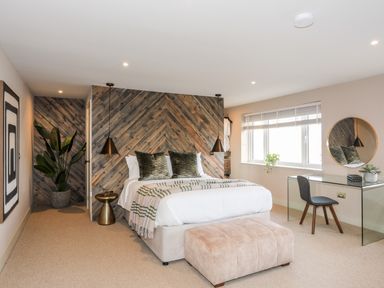 A bedroom with a bed desk chair mirror and plant at The Hayloft in Llanfechell