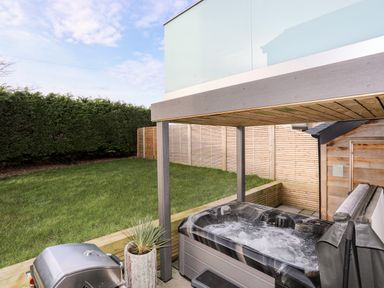 A backyard with a hot tub grill plant and wooden fences at The Hayloft in Llanfechell