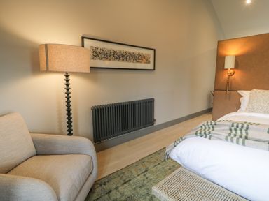 A bedroom with a bed sofa lamp and framed artwork on the wall at Garden House in Llanfechell