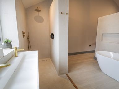 A bathroom with a walk-in shower, a white rectangular sink with gold faucets, a white bathtub, and a small plant on the windowsill at Garden House in Llanfechell