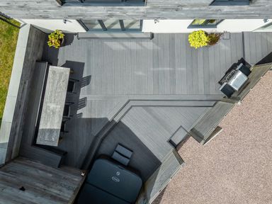 A rooftop patio with a dining table and chairs a barbecue and plants on a deck at The Farmhouse in Llanfechell