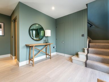 An entryway with wooden table mirror lamp and stairs with carpet at The Farmhouse in Llanfechell