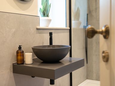 A bathroom sink with a round basin on a floating countertop next to a soap dispenser and cup at The Farmhouse in Llanfechell