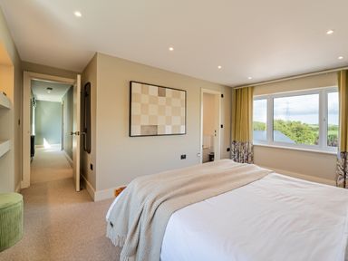 A bedroom with a bed near a window and a hallway at The Farmhouse in Llanfechell