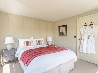 A bedroom with a double bed two bedside tables with lamps two bathrobes hanging on a door and a framed picture on the wall at The Farmhouse in Llanfechell
