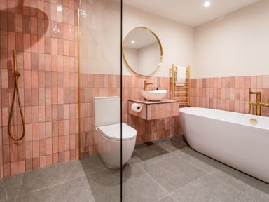 A bathroom with a shower area a toilet a wall-mounted sink a round mirror a bathtub and a towel rack at The Farmhouse in Llanfechell