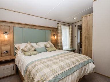 A bedroom with a double bed pillows bedside cabinets window and wardrobe at Ambleside in Cullompton