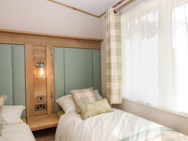 A bedroom with two single beds with green headboards and plaid curtains at Ambleside in Cullompton