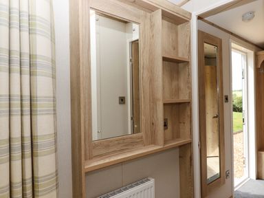 A wooden framed mirror and shelves next to a door with a long mirror at Ambleside in Cullompton