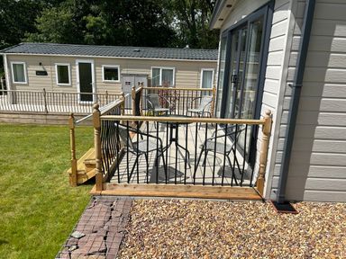 An outdoor patio area with four chairs and a small table near a mobile home in Cullompton