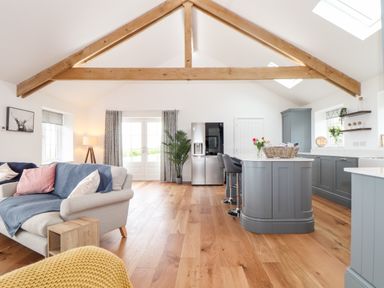 An open plan living room and kitchen with wooden beams and wooden floor at Trevilges Cottage in Trewennack near Helston