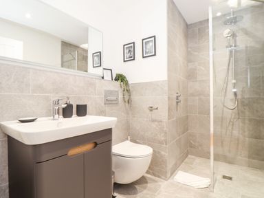 A bathroom with a sink, toilet, walk-in shower, mirror, and wall decorations at Trevilges Cottage Trewennack near Helston