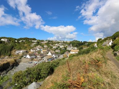 A coastal village with houses on a hillside under a blue sky at Trevilges Cottage Trewennack near Helston