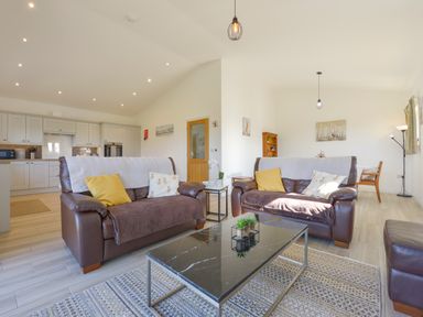 A living room with two brown leather sofas and a black coffee table with plants at The Linhay in Lapford