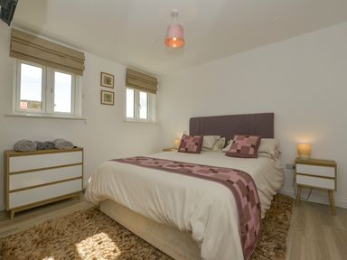 A bedroom with a bed and bedside tables with lamps and a dresser with towels at The Linhay in Lapford