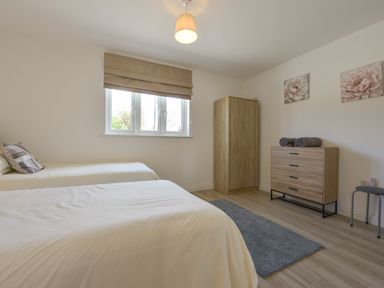 A bedroom with two single beds a wooden wardrobe a wooden dresser and a window at The Linhay in Lapford