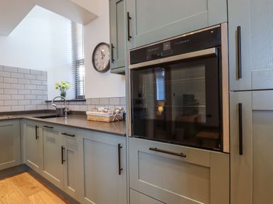 A kitchen with cabinets a built in oven a countertop with a sink and a clock on the wall at The Old Chapel in Ilsington