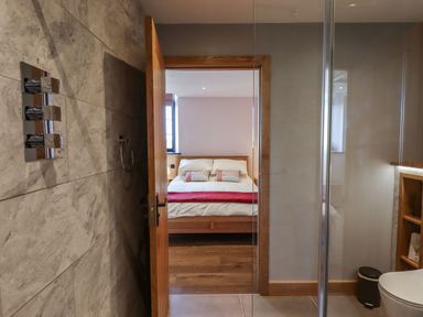 A bathroom with a shower and a door open to a bedroom with a bed at The Old Chapel in Ilsington