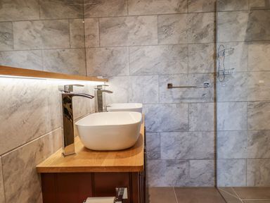 A bathroom with two white vessel sinks on a wooden countertop and a tiled wall at The Old Chapel in Ilsington