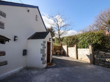 An outdoor seating area with a table and chairs next to a white building with stone accents and a wooden door at The Old Chapel in Ilsington