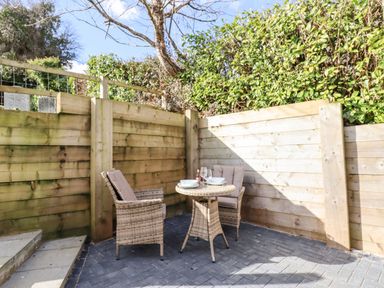 An outdoor patio with two chairs and a small round table set with plates and glasses at The Old Chapel in Ilsington