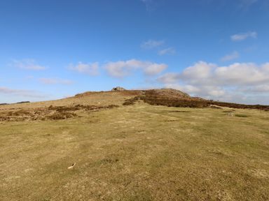 An open grassy hill under a blue sky with clouds at The Old Chapel in Ilsington