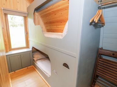 A small room with built-in bunk beds a wooden window cabinet and hanging wooden chairs at Llugwy Pod in Capel Garmon near Betws-Y-Coed
