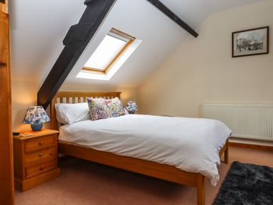 A bedroom with a wooden bed and two bedside tables with lamps under a skylight window at Northwood Barn in Okehampton