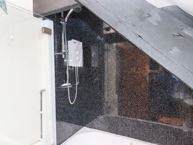 A shower area with a showerhead and control unit under a sloped ceiling at Northwood Barn in Okehampton