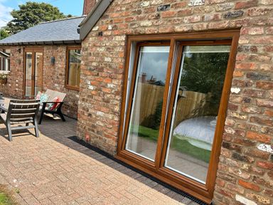 A brick exterior patio area with outdoor chairs and sliding glass doors reflecting a bed at The Annexe in Bridlington