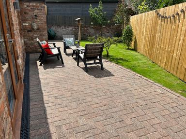 A garden patio with four wooden chairs, a small table, a grass lawn, plants, and a wooden fence at The Annexe in Bridlington