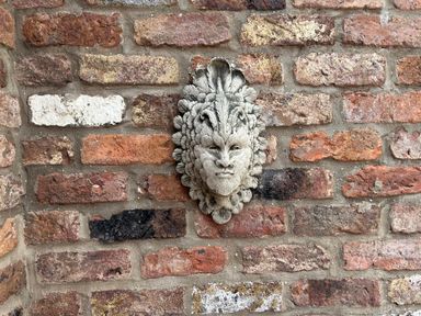 A decorative stone face mounted on a red brick wall