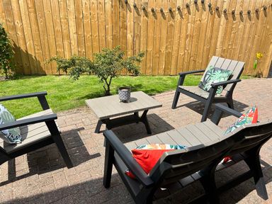 An outdoor patio area with a small table and four chairs with cushions and a potted plant on the table at The Annexe in Bridlington