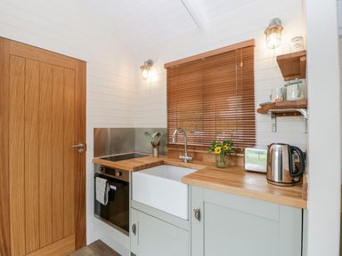 A kitchen with wooden countertops a white sink a kettle toaster and a window with blinds at Willow Kemble