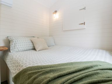 A small bedroom with a bed covered in patterned sheets and a green blanket at Willow in Kemble