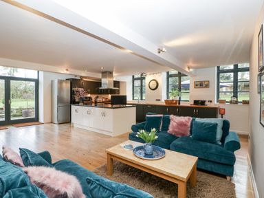 An open plan living room and kitchen with blue sofas and a wooden coffee table at Owl Barn in Marston Stannett near Leominster