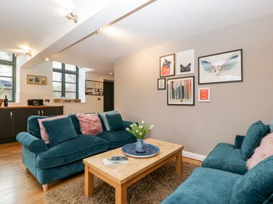 A living room with two teal sofas a wooden coffee table with flowers and framed pictures on the wall at Owl Barn Marston Stannett near Leominster