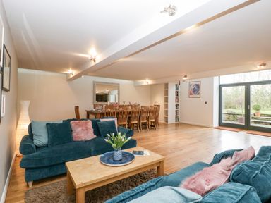 A living room and dining area with blue sofas and a wooden table at Owl Barn in Marston Stannett near Leominster