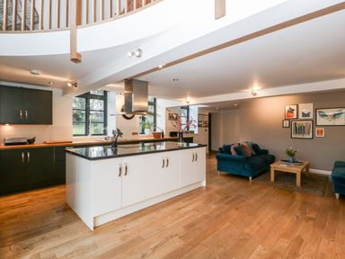 A kitchen with an island and a seating area with sofas and a coffee table at Owl Barn in Marston Stannett near Leominster