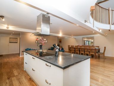 A kitchen island with stove and utensils a dining table with chairs and a living room area at Owl Barn Marston Stannett near Leominster