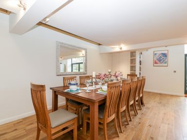 A dining room with a wooden table and ten chairs set with plates glasses and flowers at Owl Barn Marston Stannett near Leominster