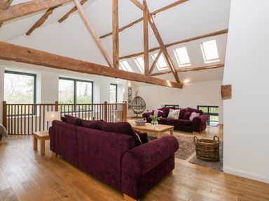 A sitting area with purple sofas a wooden coffee table and exposed wooden beams at Owl Barn Marston Stannett near Leominster