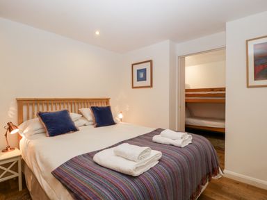 A bedroom with a double bed with folded towels on a blanket and an adjacent room with bunk beds at Owl Barn in Marston Stannett near Leominster