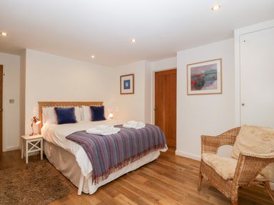 A bedroom with a double bed with pillows and folded towels beside a wicker chair at Owl Barn in Marston Stannett near Leominster