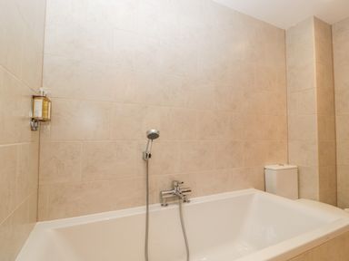 A bathroom with a white bathtub shower head and toilet at Owl Barn Marston Stannett near Leominster