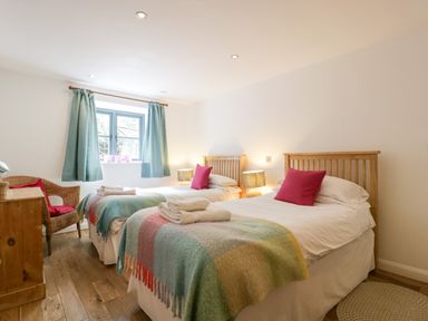 A bedroom with two single beds side by side with wooden headboards and colorful blankets at Owl Barn Marston Stannett near Leominster